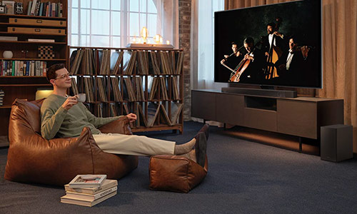 A man enjoys an immersive symphony concert with Dolby Atmos Music in his living room.