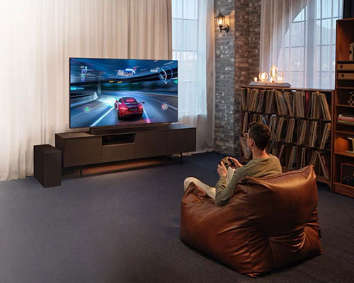 A man enjoys an immersive 3D-like gaming experience with Game Mode Pro on his Samsung Ultra Slim Soundbar.