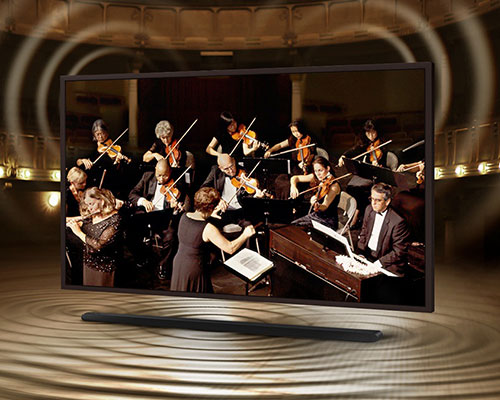 The Frame is showing an orchestra on its screen. The Soundbar is below The Frame with sound ripples coming out of it to show that the sound of the speakers on The Frame and Soundbar are perfectly synced. 