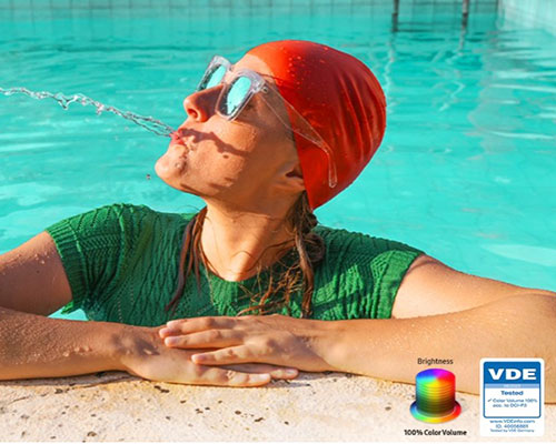 A woman is spitting out water in the pool. All the colors in the image become vivid as the brightness level increases. VDE tested logo is on display.
